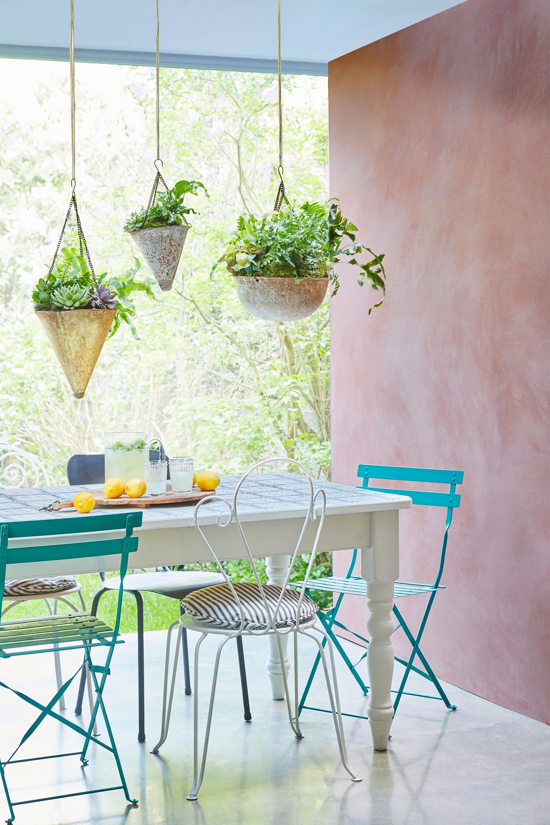 jedilnica na terasi z roza kredo pobarvanimi stenami in visečimi rastlinami