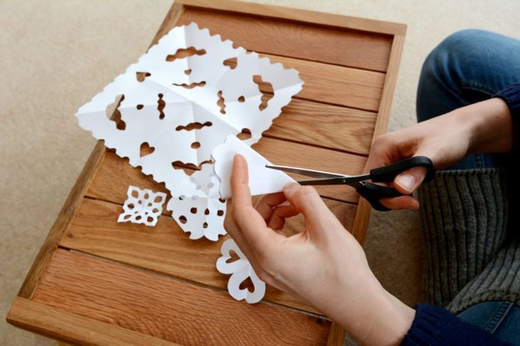 жена, режеща хартиени снежинки
