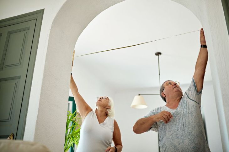 по-възрастен мъж и жена измерват вратата на хола
