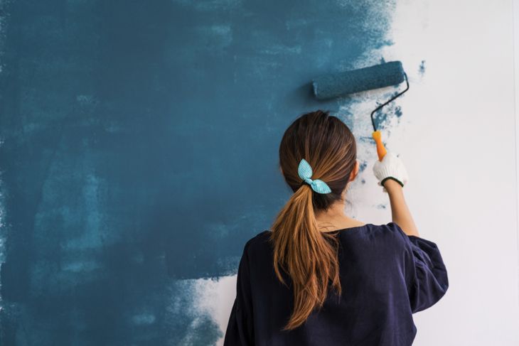 大胆な青緑色の壁を描く女性