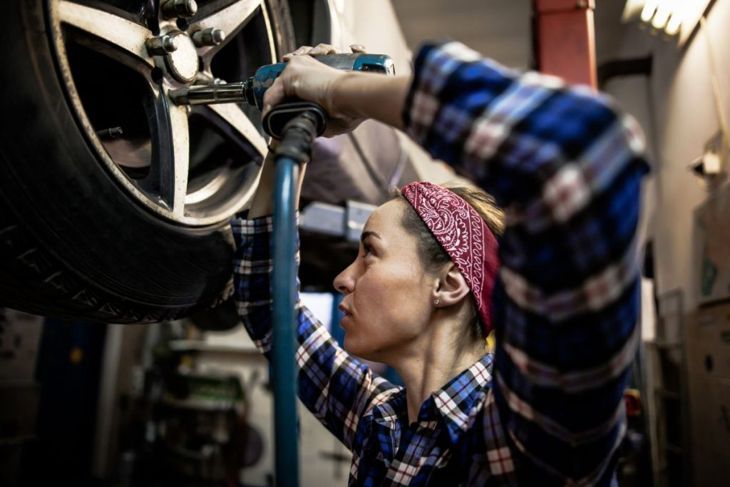 Жена механик, работеща в сервиз за автомобилни гуми