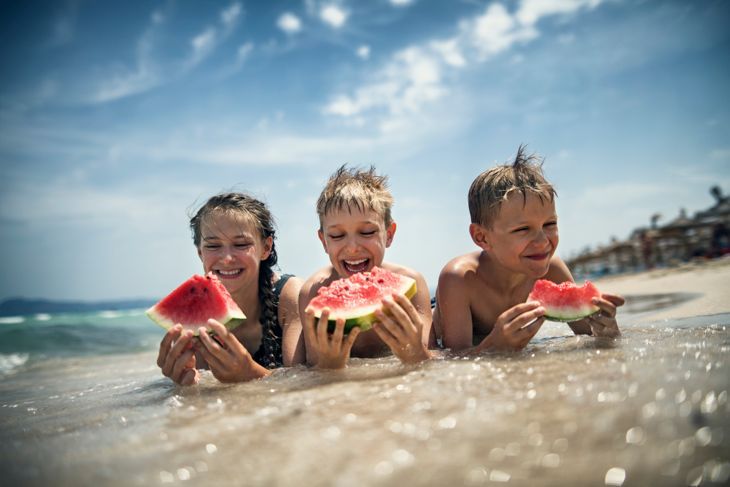 ビーチでスイカを食べる幸せな子供たち