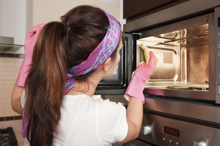 Жена почиства микровълнова печка