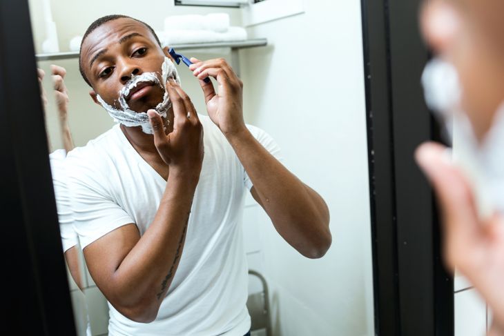 Портрет на красив млад черен мъж, който се бръсне в домашна баня