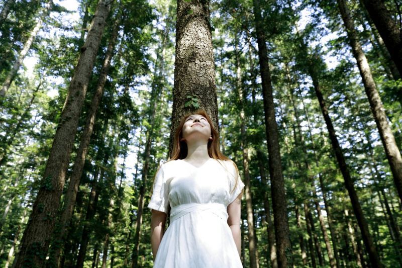 жена, облегната на дърво в гората