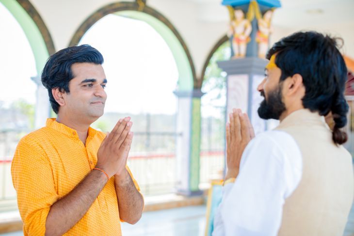 Посетител на храма и индуистки свещеник се поздравяват