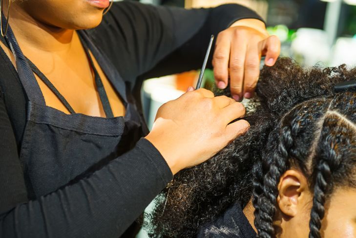 Отблизо африкански фризьор сплетена коса на афро-американска клиентка във фризьорския салон.