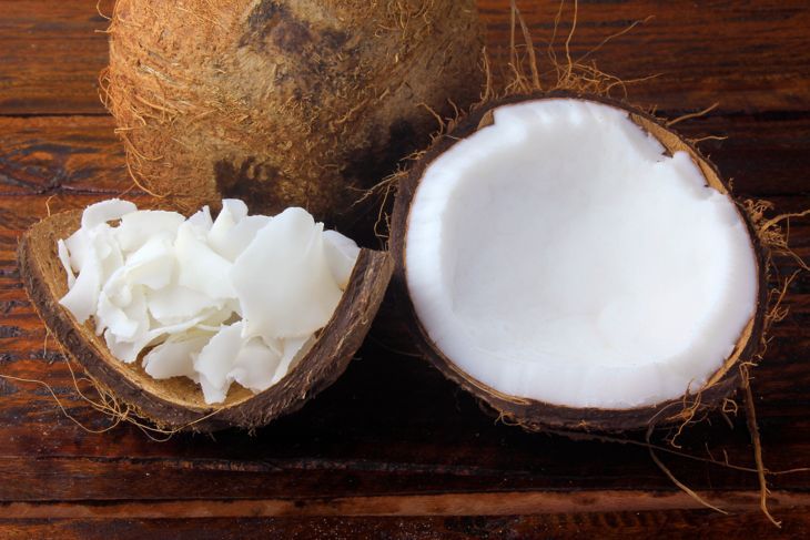 пресни кокосови стърготини и чипс, поставени в кора и черупки, изолирани върху селски дървен фон