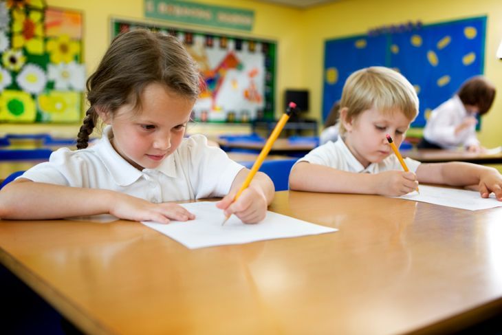 Двойка сладки 5-годишни деца от началното училище, които работят усилено върху обучението си в класната стая.