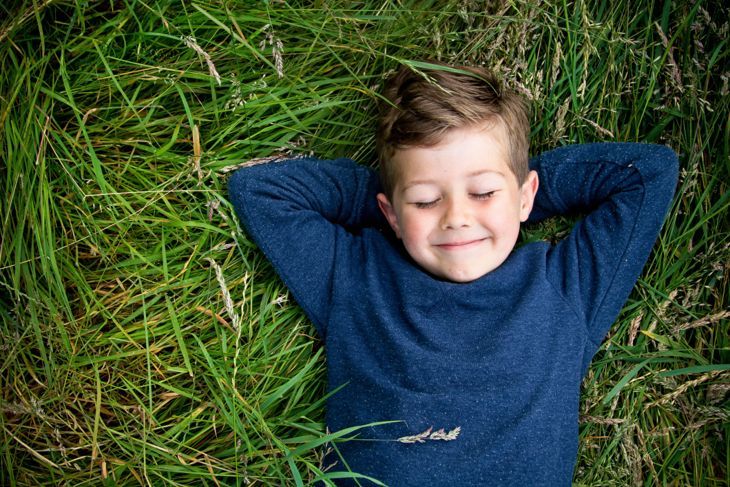 Портрет на усмихнато момче, лежащо на тревата