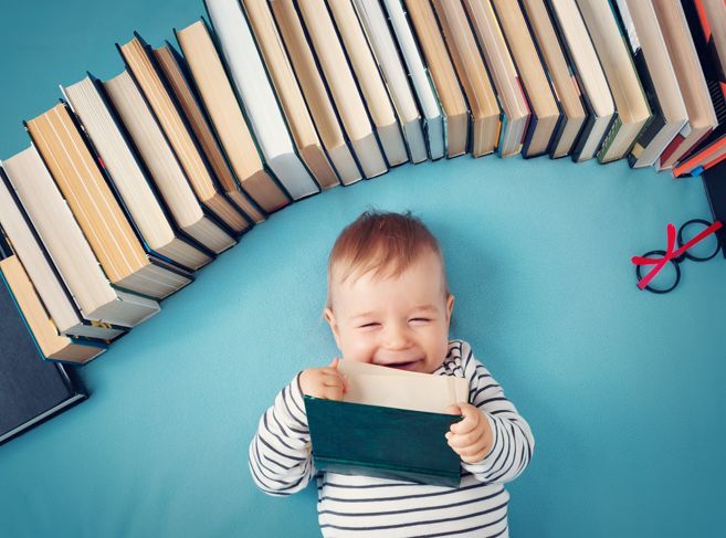 眼鏡の本の中の1歳の赤ちゃん。幸せな小さな子供が読んでいます。