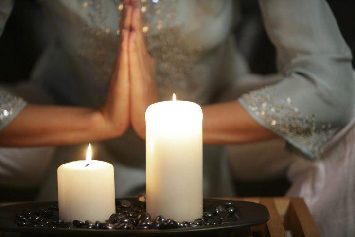 Духовна жена, практикуваща йога със свещи