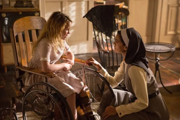 車椅子に座って修道女が話しかける少女